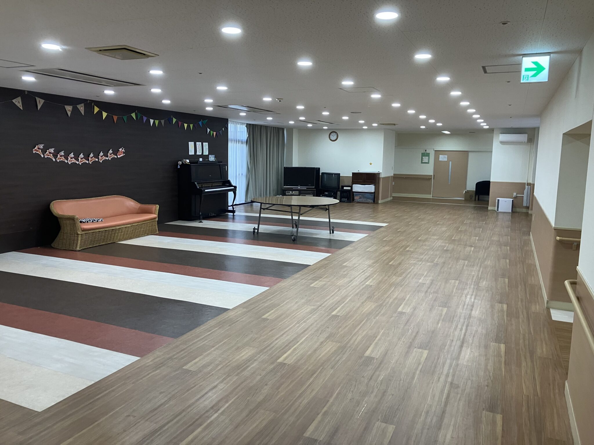 介護施設の広々とした共用スペース。ピアノ、ソファ、テレビなど多用途に使用できる設計。